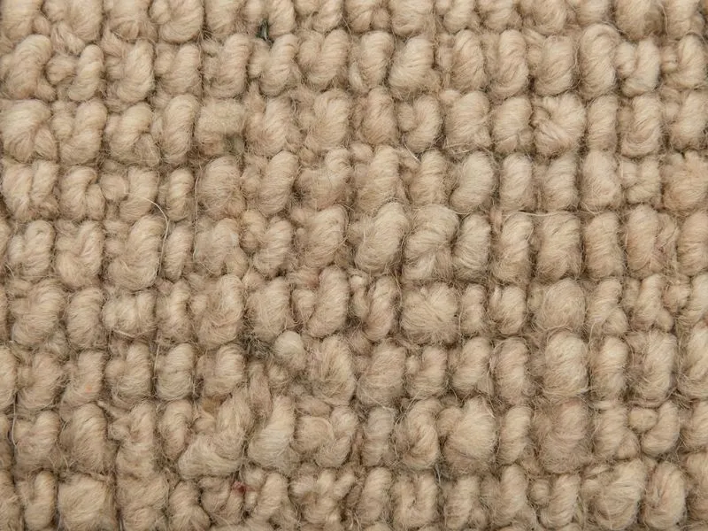 Macro close-up view of the hand-knotted backing of an authentic Moroccan Berber area rug showing irregular wool knots.